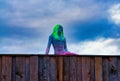 Sculpture of a woman with vibrant green hair under a cloudy sky in Jois, Austria