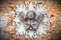 Sculpture of a wooden angel against an old classical plaster frame Royalty Free Stock Photo