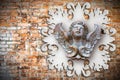 Sculpture of a wooden angel against an old classical plaster frame Royalty Free Stock Photo