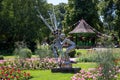 Sculptured statue of a child blowing notes from a tuba with the bandstand in the garden