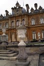 Sculptured urns on pedestals in front of domed sculptured facade with columns