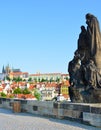 Sculptures on famous Charles Bridge in Prague, Czech Republic with blue sky. Prague Castle and other historical buildings in Royalty Free Stock Photo