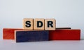 SDR - acronym on wooden cubes on a background of colored block on a light background