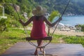 Sea background. Outdoors lifestyle fashion portrait stunning girl sitting back on swing on the beach. Wearing stylish blue dress