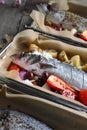 Sea bass in a baking dish, close-up, selective focus. Baking fish with vegetables and spices in a sheet pan.