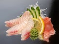 Sea bass sashimi with ginger, wasabi, cucumber and lemon on a shiny surface. Japanese kitchen Royalty Free Stock Photo