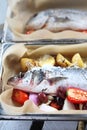 Sea bass with vegetables in a baking dish, close-up, selective focus. Baking fish in a sheet pan with parchment paper.