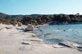 Sea beach with hilly landscape on sunny blue sky. Stony beach with blue water and green trees. Summer vacation in tropic