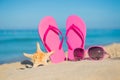 The sea, beach, sand and women's accessories: pink flip-flops, sunglasses and starfish Royalty Free Stock Photo