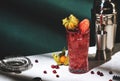 Sea breeze alcoholic cocktail with vodka, cranberries, grapefruit juice, orange and ice, decorated with physalis. Dark green Royalty Free Stock Photo