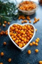 Sea buckthorn berries in a heart shaped bowl, orange healthy berries, macro. Rustic style, top view Royalty Free Stock Photo