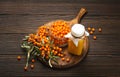 Sea buckthorn healthy drink in bottle, ripe berries in glass jar and branches with leaves top view on dark wooden rustic Royalty Free Stock Photo