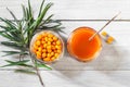 Sea buckthorn jam and fresh berries in glass jars and a green branch on a white wooden table Royalty Free Stock Photo
