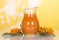 Sea buckthorn juice in a jug and branches on yellow Royalty Free Stock Photo