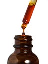 Sea buckthorn oil from a pipette drips into a bottle of oil