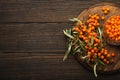 Sea buckthorn ripe berries in glass jar and branches with leaves top view on dark wooden rustic background, great for Royalty Free Stock Photo