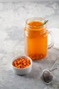 Colorful hot sea buckthorn tea with rosemary and fresh sea buckthorn berries on a grey table. Vitamin drink.