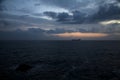 Sea on a cloudy day at dusk with a cargo ship on the horizon Royalty Free Stock Photo