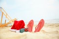 Santa Claus hat with gift box and flip-flops on sea coast. Christmas vacation Royalty Free Stock Photo