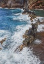 Sea coast with rocky cliffs. Blue water and big stones on the seashore. Rocks on the coast, summer background. Royalty Free Stock Photo