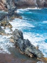 Sea coast with rocky cliffs. Blue water and big stones on the seashore. Rocks on the coast, summer background. Royalty Free Stock Photo