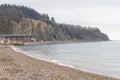 A sea coastal strip of land, cloudy weather, a lonely figure of a woman walking along the seashore on a summer day.