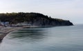 A sea coastal strip of land, cloudy weather, a lonely figure of a woman walking along the seashore on a summer day.