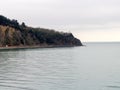 A sea coastal strip of land, cloudy weather, a lonely figure of a woman walking along the seashore on a summer day.