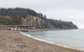 A sea coastal strip of land, cloudy weather, a lonely figure of a woman walking along the seashore on a summer day.