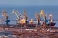 Sea commercial port at night in Mariupol, Ukraine. Industrial view. Cargo freight ship with working cranes bridge in sea port Royalty Free Stock Photo