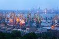 Sea commercial port at night in Mariupol, Ukraine. Industrial view. Cargo freight ship with working cranes bridge in sea port