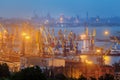 Sea commercial port at night in Mariupol, Ukraine. Industrial view. Cargo freight ship with working cranes bridge in sea port