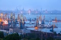 Sea commercial port at night in Mariupol, Ukraine. Industrial view. Cargo freight ship with working cranes bridge in sea port