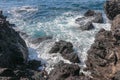 The sea currents blend wildly at the rocky shore. Power and energy of the ocean. Lava-created rocks in the sea. Sea surf arrives