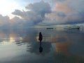 The sea with dramatic sky clouds and silhouette of a woman walking on beach with the water reflection. Royalty Free Stock Photo