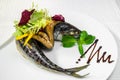 Sea fish, dressed with vegetables and olives on a white plate. Sea fish, dressed with vegetables and olives on a white plate. Hori