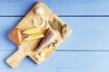 Sea fish, onion, potato, lemon and natural seasoning on cutting board. Top view on wooden table with copy space Royalty Free Stock Photo