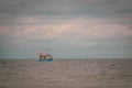 on the sea floats a fishing boat, which is surrounded by many seagulls and the sky is full of clouds Royalty Free Stock Photo