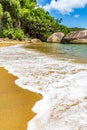 Sea foam advancing over the sand on the beach surrounded by rainforest Royalty Free Stock Photo