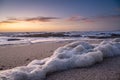 Sea foam lying on beach at dusk. Low angle, close up with beautiful gradient sky Royalty Free Stock Photo