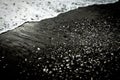 Sea foam wave on black sand beach with stones. Black and white Royalty Free Stock Photo