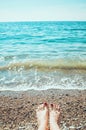Sea foam, waves and naked woman feet on a sand beach. Girl legs relaxing. Vacation holidays, relax, summer background