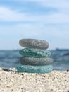 Sea glass on beach sand with seascape background. Beachcombing. Harmony and balance concept. Vertical composition