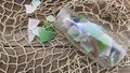 Sea glass vertical on  fishing net background in bottle Royalty Free Stock Photo
