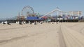 Sea gulls on sunny sandy california beach, classic ferris wheel in amusement park on pier in Santa Monica pacific ocean resort.