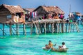 Sea Gypsy family on their sampan near their huts on stilts