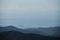 Sea on horizon and small silhouette of cargo ship in distance. Clear warm weather and haze stands over sea. Beautiful view from