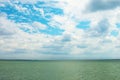 Sea landscape. Sea bank and cloudy sky. Green water surface, forest on horizont line and blue sky with clouds. Royalty Free Stock Photo