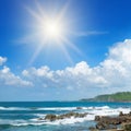 Sea landscape with beautiful waves, rocky shore and bright sun on a blue sky Royalty Free Stock Photo