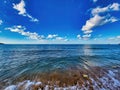 Sea landscape. White waves on the beach with black sand, a distant bale and white clouds. Rock in the sea sky. Hight quality photo